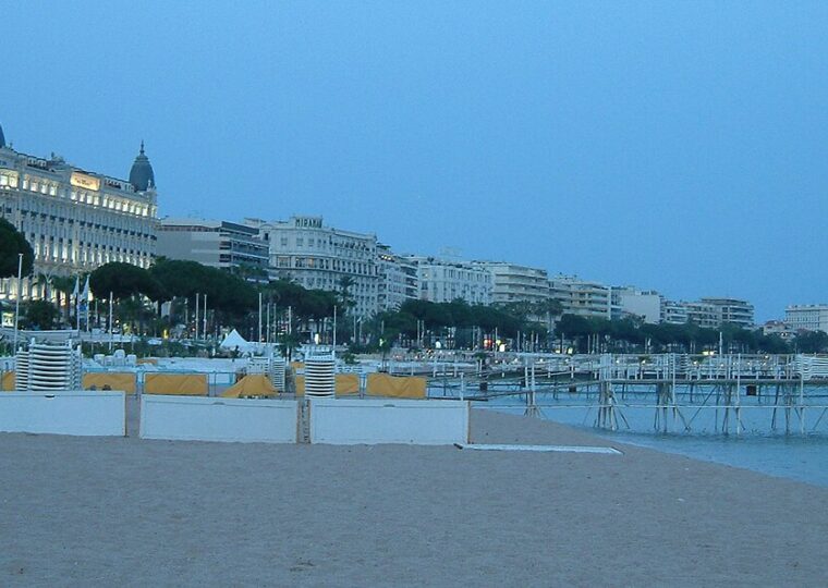 La promenade de la Croisette vue depuis la plage de Cannes, avec les coupoles du Carlton au loin