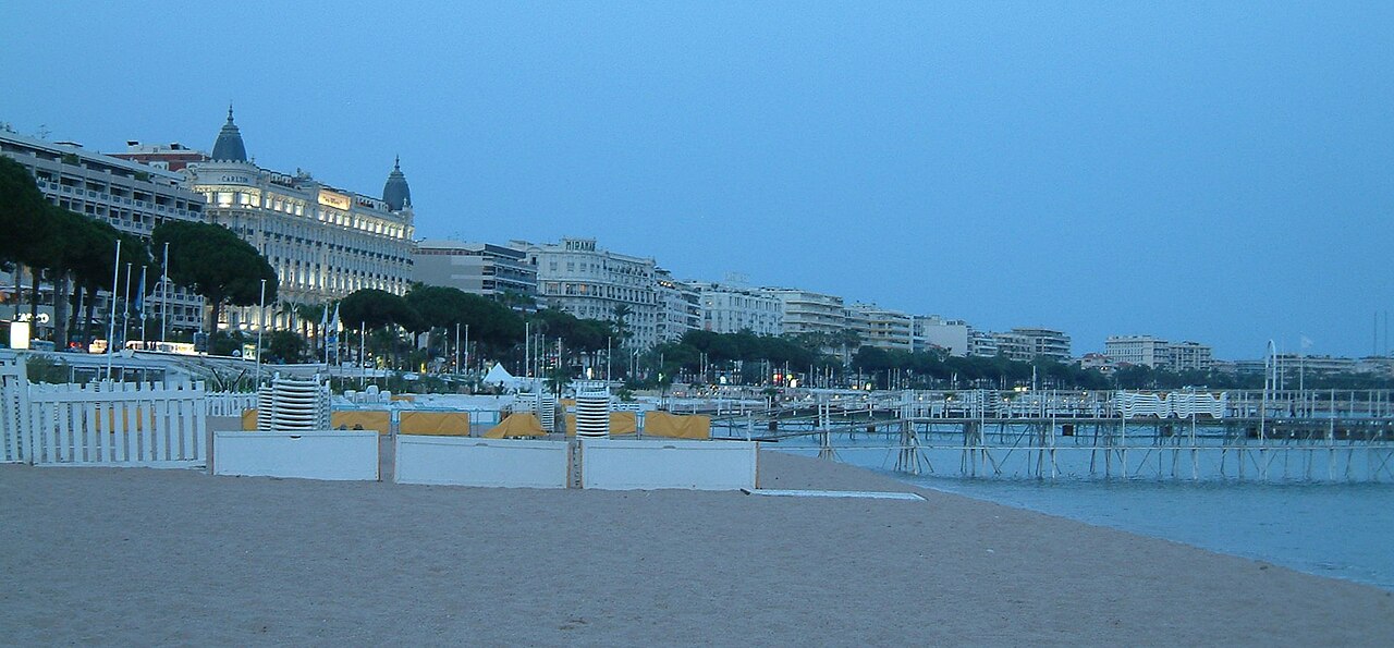 La promenade de la Croisette vue depuis la plage de Cannes, avec les coupoles du Carlton au loin