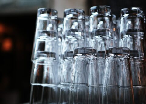Verres de bar empilés en pyramide sur un comptoir sombre