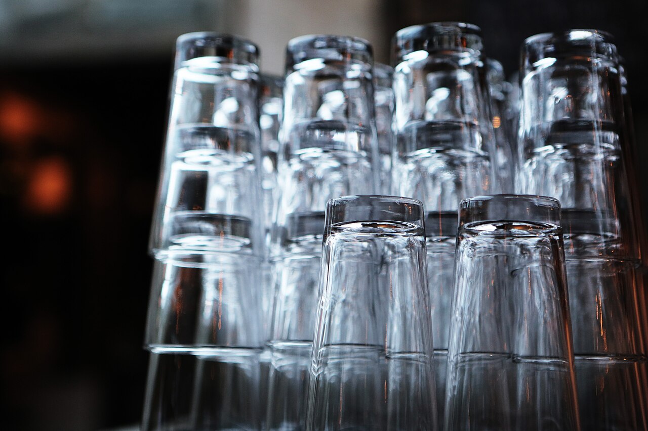 Verres de bar empilés en pyramide sur un comptoir sombre