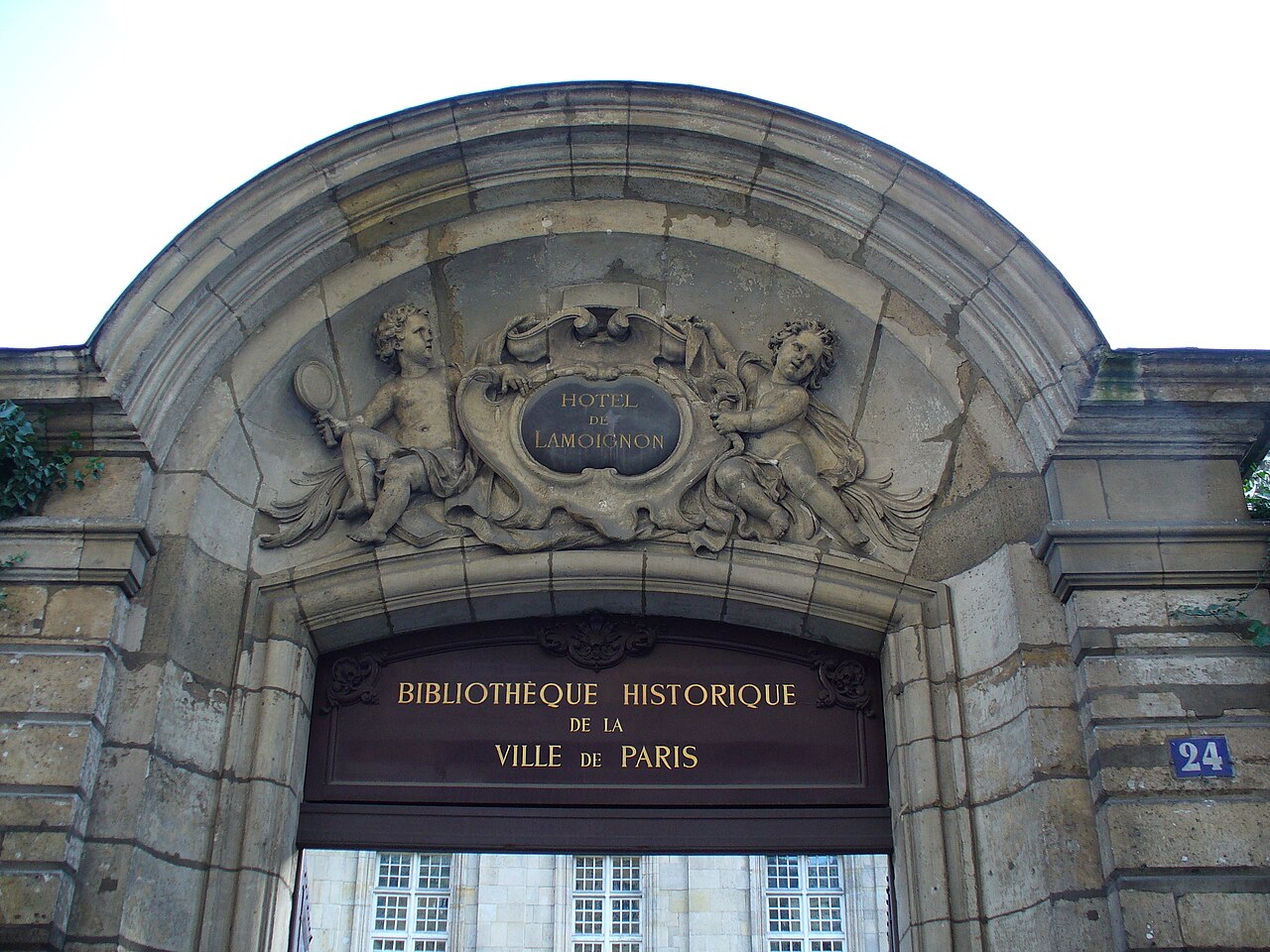 Le fronton sculpté du portail de l'hôtel de Lamoignon, avec l'enseigne de la Bibliothèque historique de la Ville de Paris
