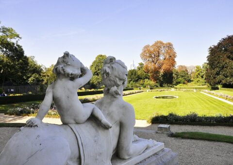 Une sphinge de marbre portant un enfant, au premier plan des parterres du parc de Bagatelle