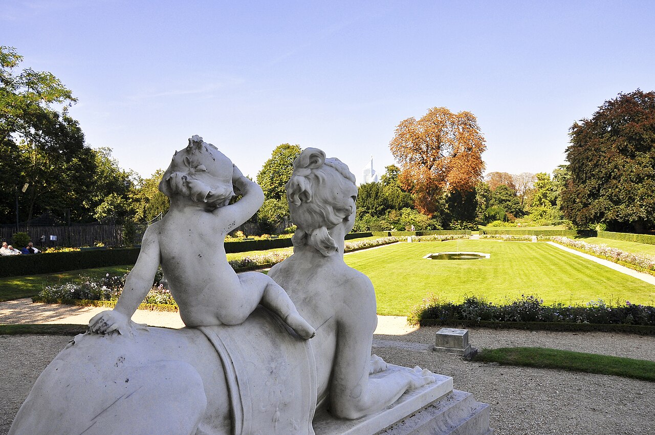 Une sphinge de marbre portant un enfant, au premier plan des parterres du parc de Bagatelle