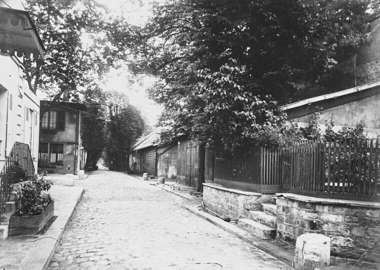 Une ruelle pavée des entrepôts de Bercy bordée de chais et d'arbres, photographiée par Eugène Atget