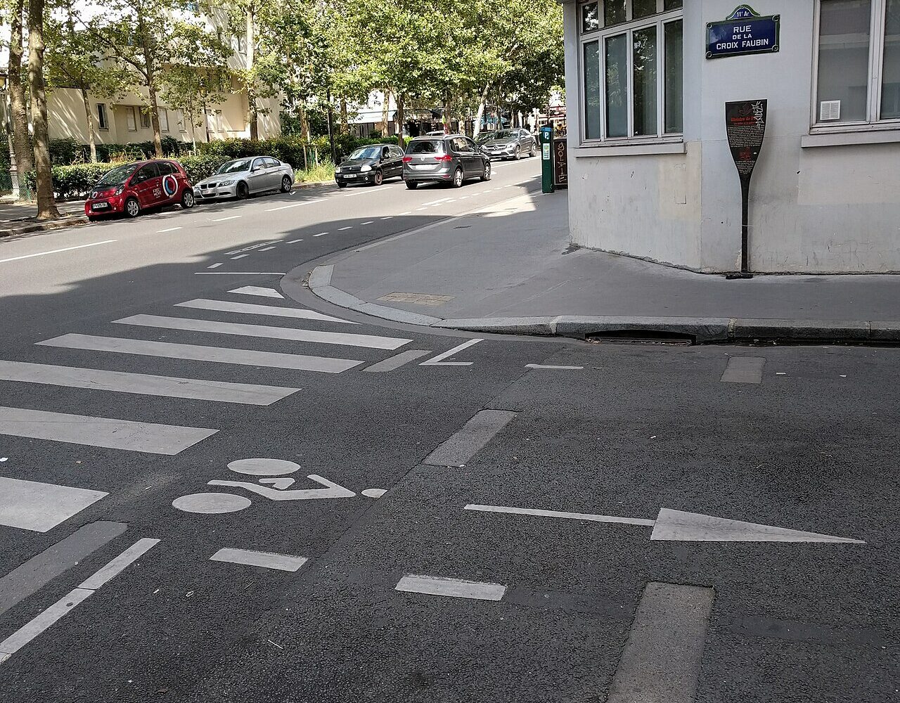Les dalles de la guillotine affleurant dans la chaussée de la rue de la Croix-Faubin, avec la plaque de rue et le panneau Histoire de Paris