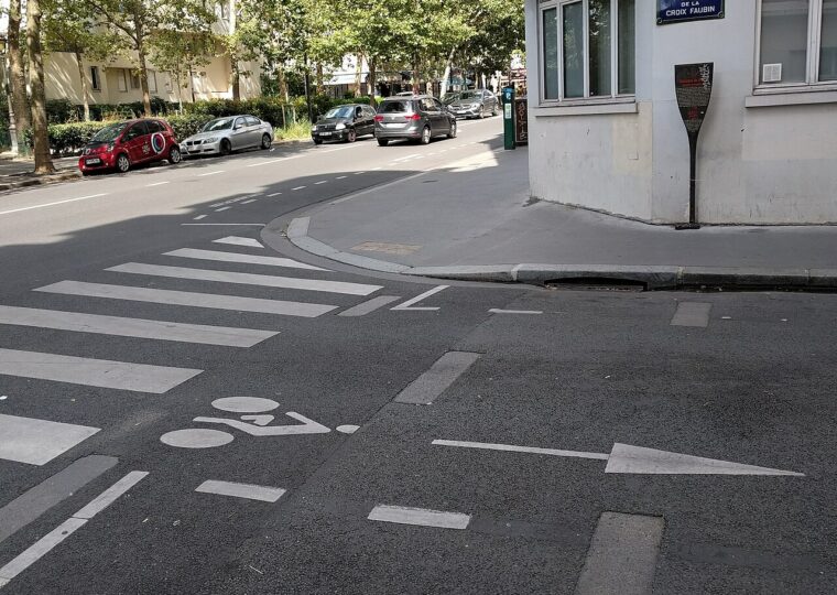 Les dalles de la guillotine affleurant dans la chaussée de la rue de la Croix-Faubin, avec la plaque de rue et le panneau Histoire de Paris