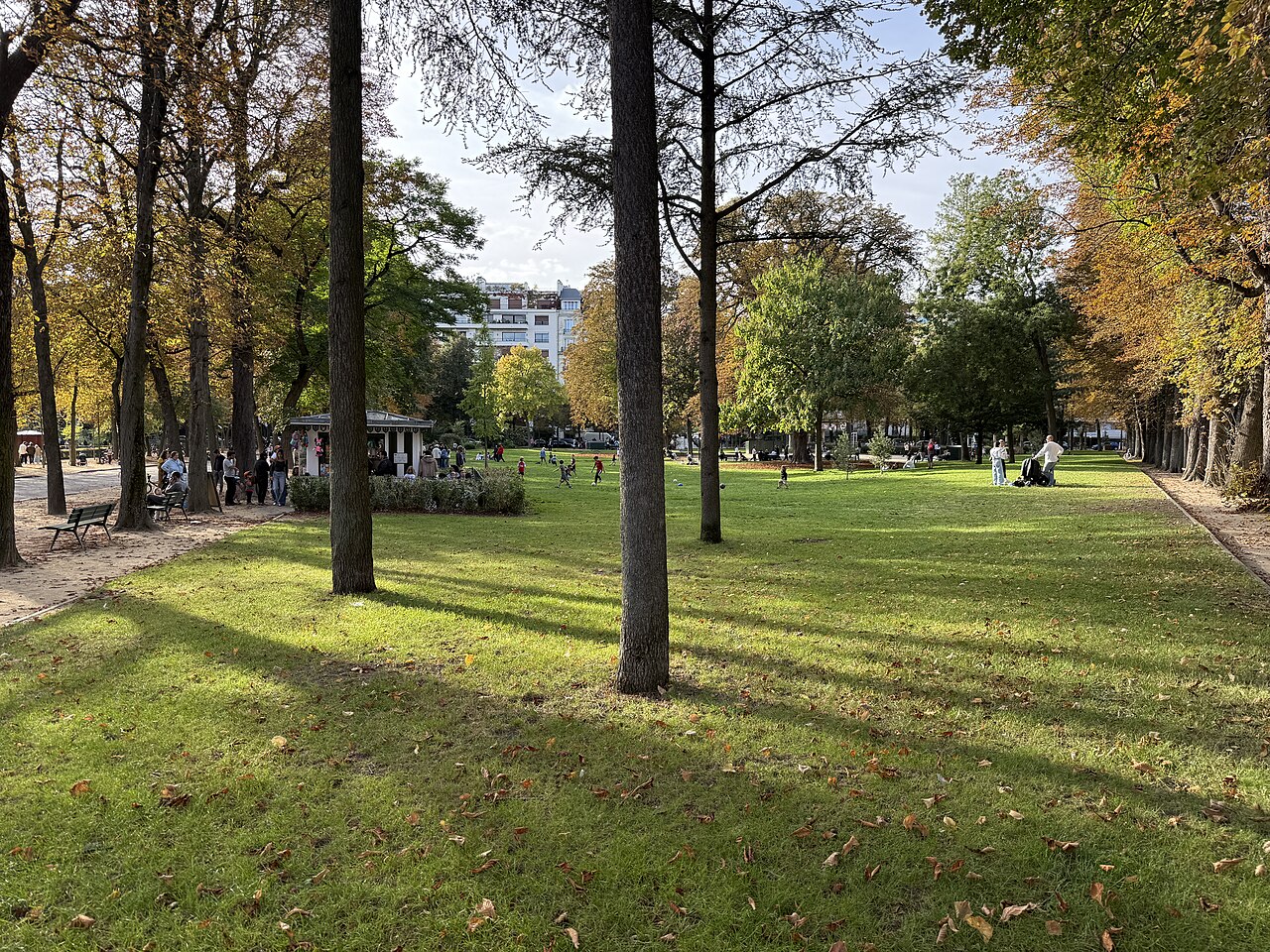 Les pelouses du jardin du Ranelagh sous les arbres à l'automne, un kiosque de confiseries au fond