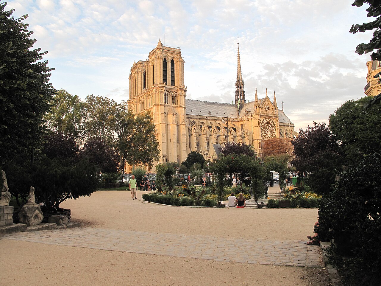 Le square René-Viviani au soleil couchant, ses massifs fleuris et le chevet de Notre-Dame de Paris au fond