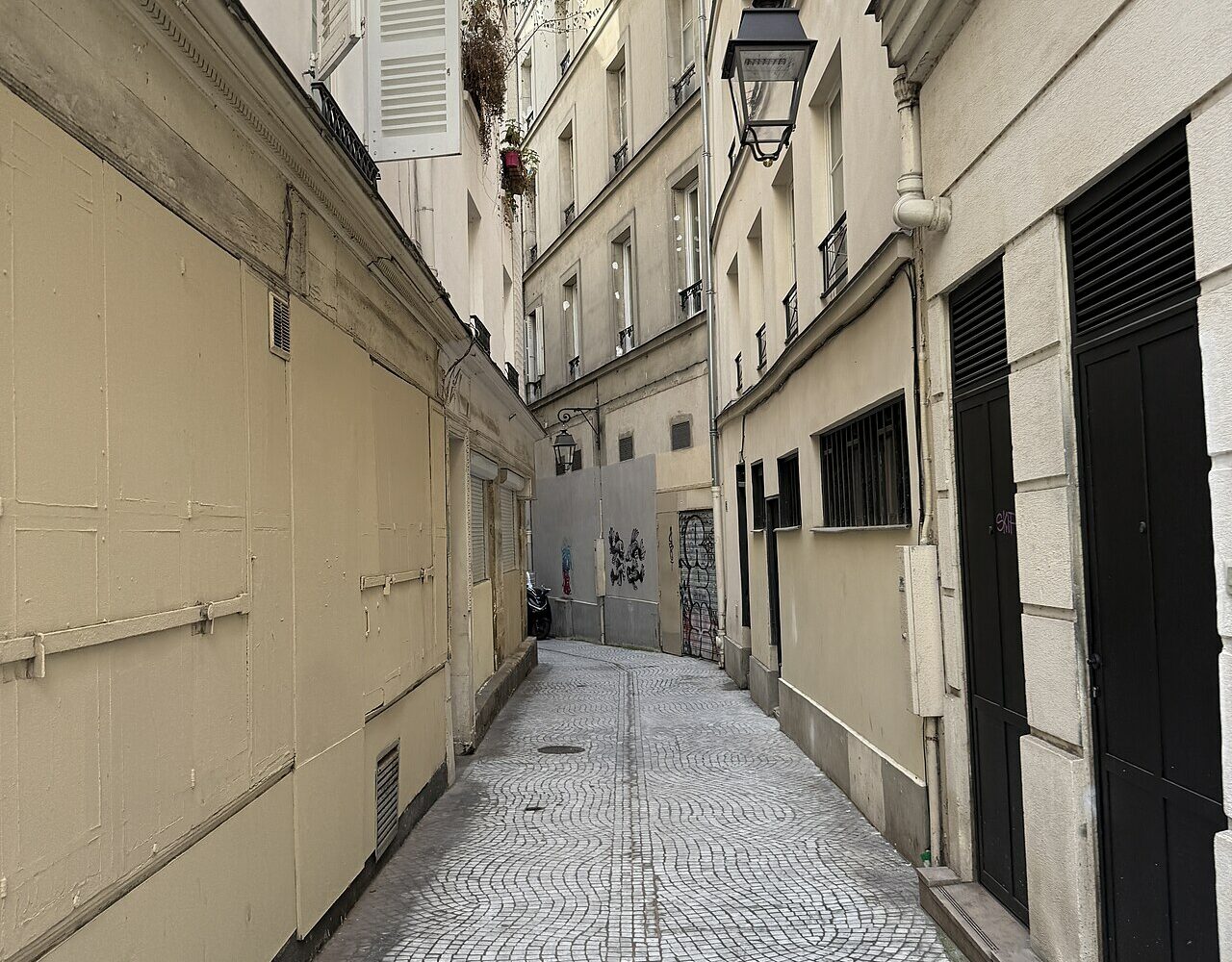 Le passage de la Trinité, venelle pavée en pente avec ses marches et sa lanterne, entre la rue Saint-Denis et la rue de Palestro