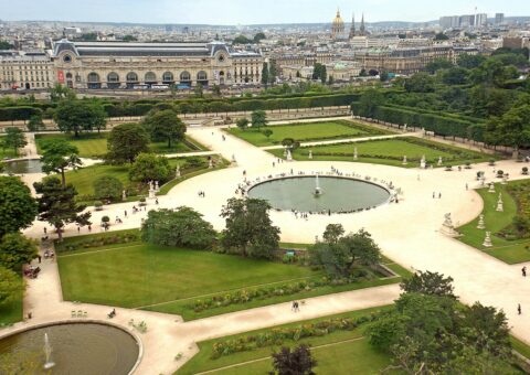 Vue plongeante sur le grand bassin rond du jardin des Tuileries, ses parterres, ses allées et la gare d'Orsay au fond