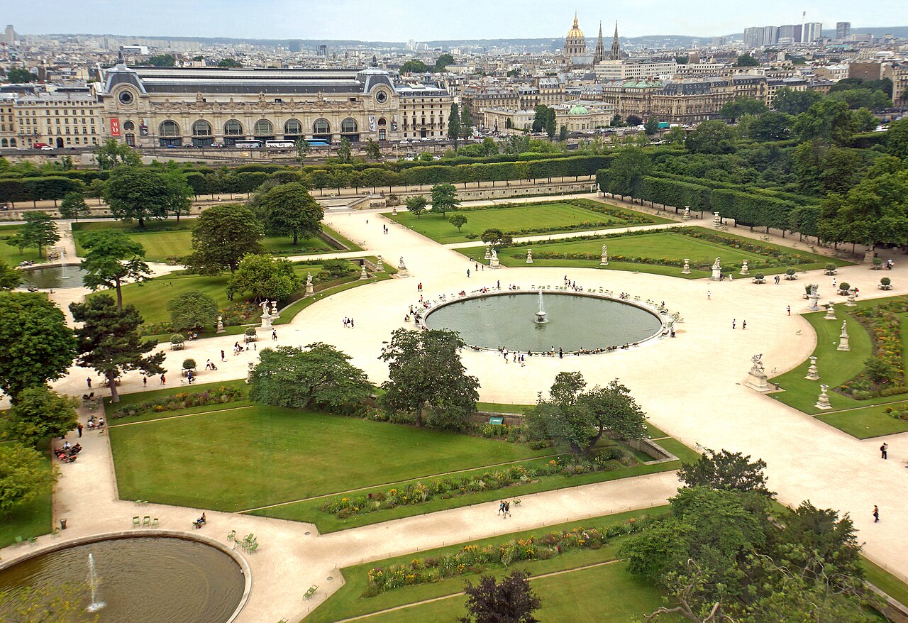 Vue plongeante sur le grand bassin rond du jardin des Tuileries, ses parterres, ses allées et la gare d'Orsay au fond