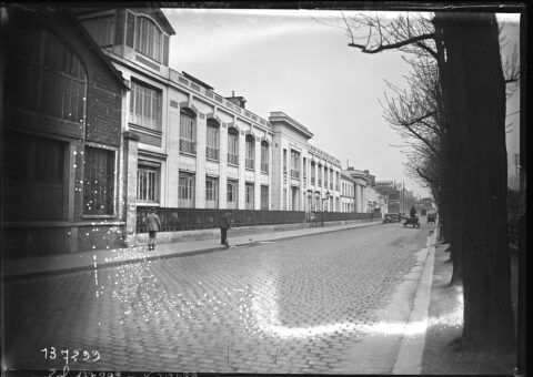 Les bâtiments de l'usine Citroën du quai de Javel en mai 1929, rue pavée et arbres, photographie de l'agence Rol