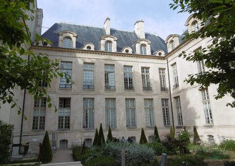 La façade classique de l'hôtel d'Albret vue depuis le jardin des Rosiers, ses ifs taillés et ses massifs