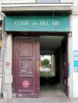 Le porche de la cour du Bel-Air au 56 rue du Faubourg-Saint-Antoine, avec son enseigne verte et la perspective pavée