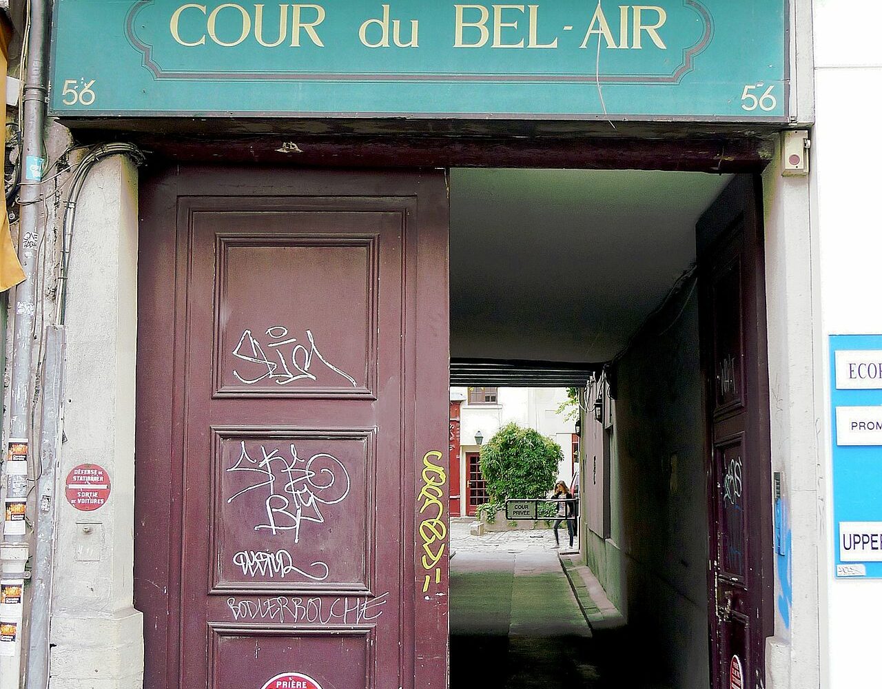 Le porche de la cour du Bel-Air au 56 rue du Faubourg-Saint-Antoine, avec son enseigne verte et la perspective pavée