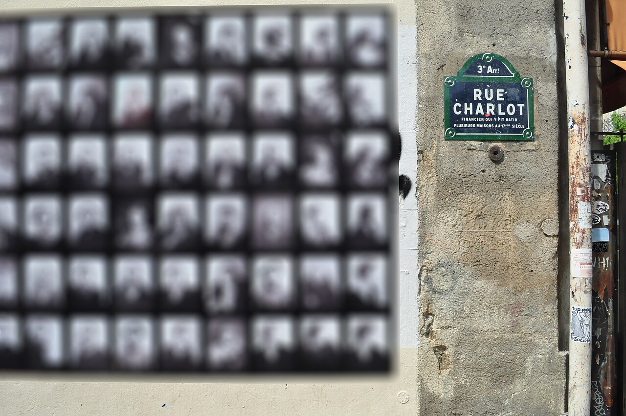 Un mur de la rue Charlot couvert d'affiches sérigraphiées, sous la plaque de la rue