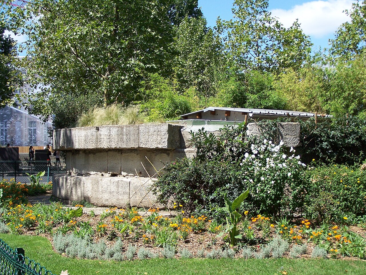 Les assises de pierre de la tour de la Liberté, vestige de la Bastille remonté au square Henri-Galli, au milieu des fleurs