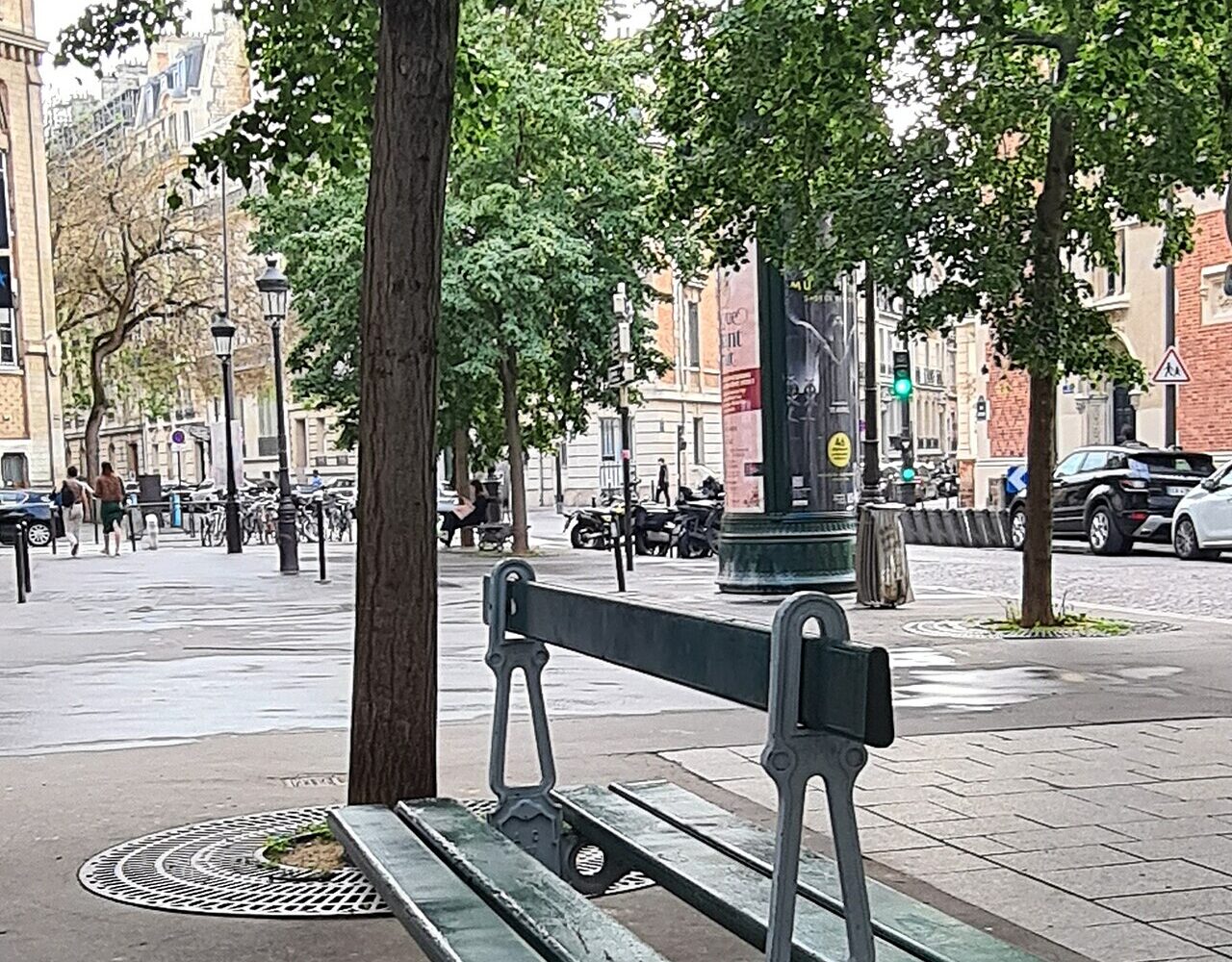 Un banc Davioud à double assise dos à dos, fonte et lattes de bois, sur la place Lévis
