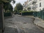 L'allée pavée de la cité des Fleurs, bordée de grilles, de jardinets et de maisons du dix-neuvième siècle