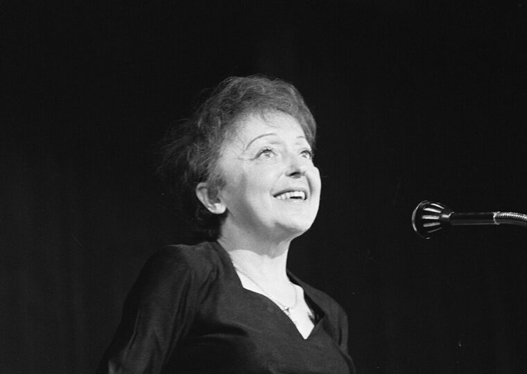 Édith Piaf chantant, le visage levé, devant un micro à Rotterdam le 13 décembre 1962