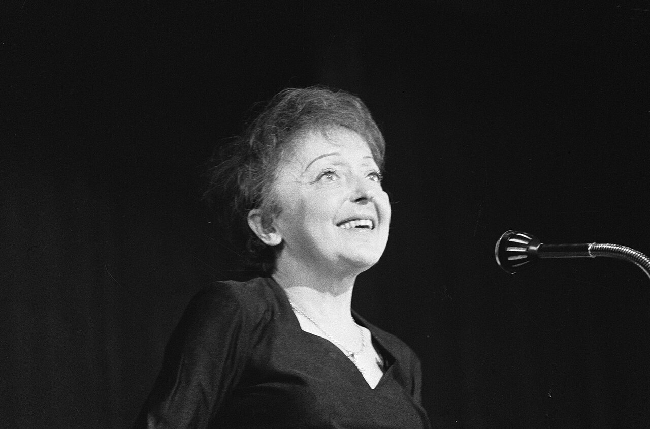 Édith Piaf chantant, le visage levé, devant un micro à Rotterdam le 13 décembre 1962
