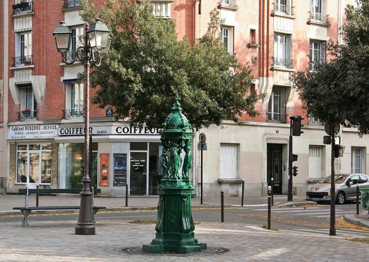 Une fontaine Wallace vert sombre, ses quatre cariatides portant le dôme aux dauphins