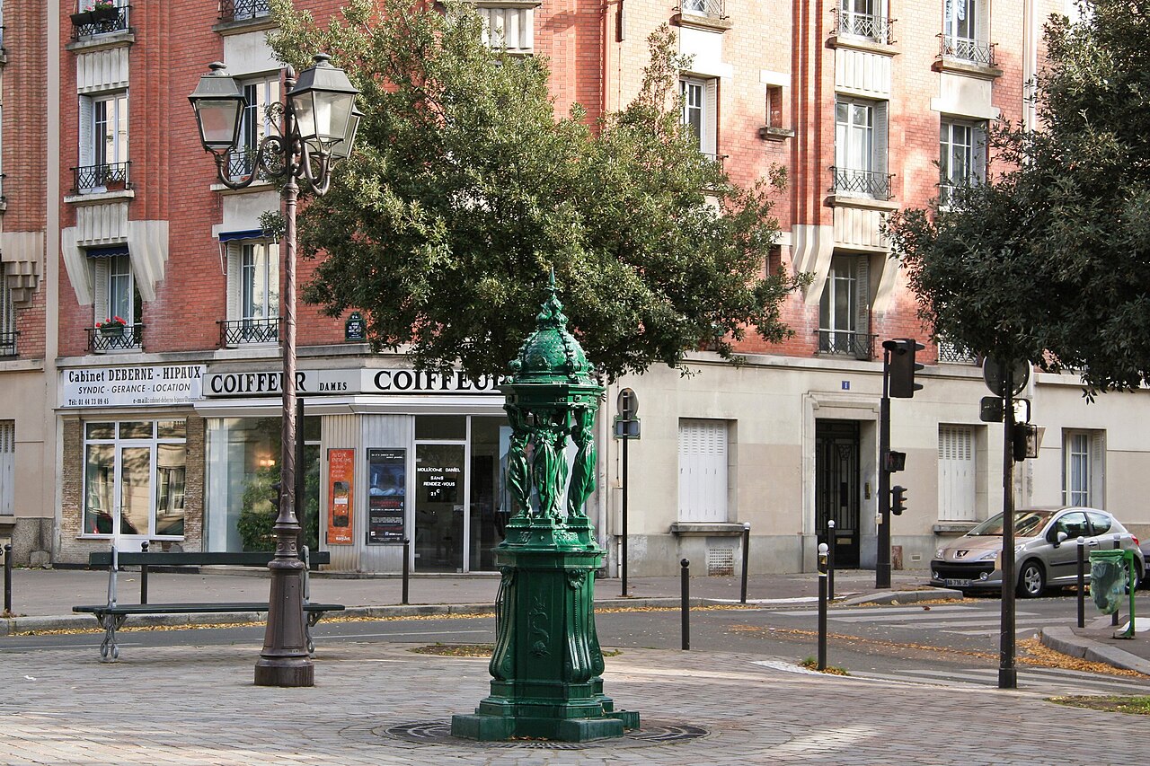 Une fontaine Wallace vert sombre, ses quatre cariatides portant le dôme aux dauphins