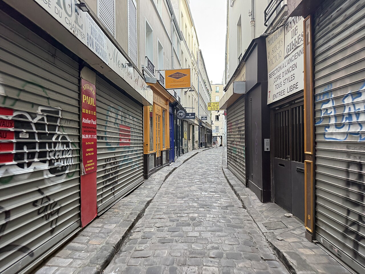 Le passage du Chantier pavé, bordé de boutiques et d'enseignes de meubles du faubourg Saint-Antoine