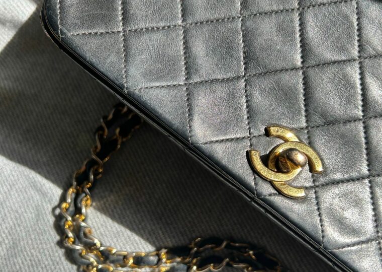 Gros plan d'un sac Chanel en cuir noir matelassé avec sa chaîne dorée entrelacée de cuir