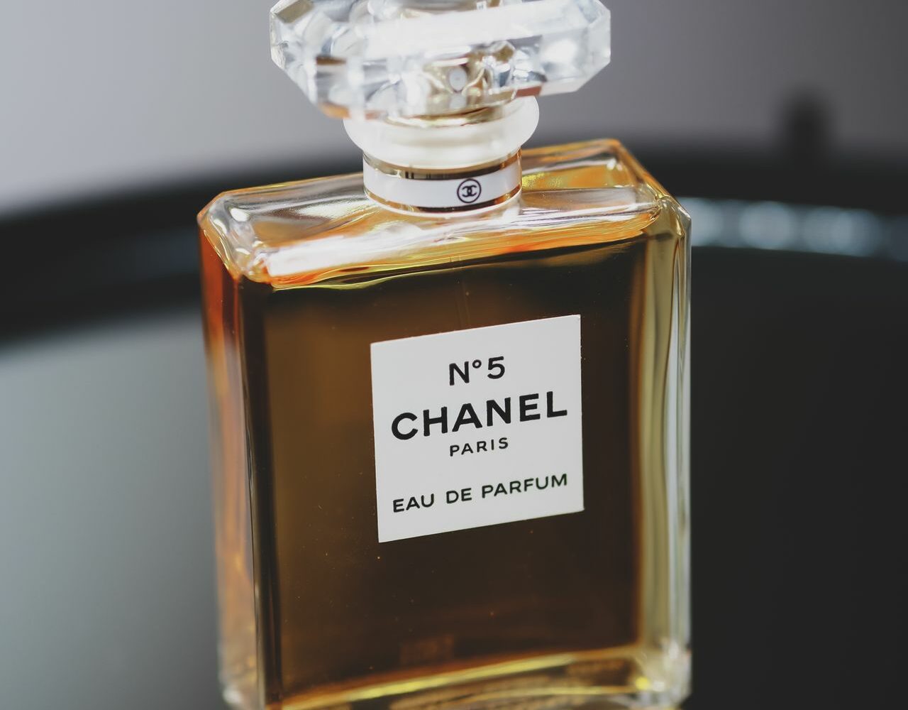 Un flacon de N°5 de Chanel posé sur un plateau sombre, sur fond gris