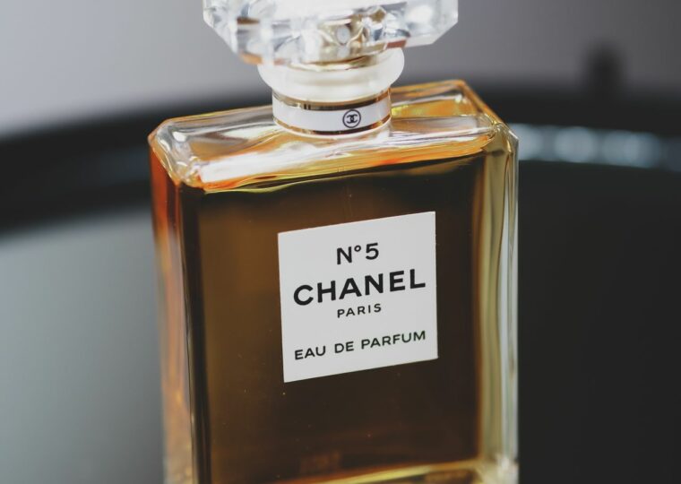 Un flacon de N°5 de Chanel posé sur un plateau sombre, sur fond gris